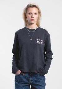 Marineblaues Langarm-T-Shirt aus Baumwolle mit einem Grafikdruck auf der Vorderseite in rosa Schrift. Lockere Passform mit rundem Halsausschnitt und dezentem Saumdetail.