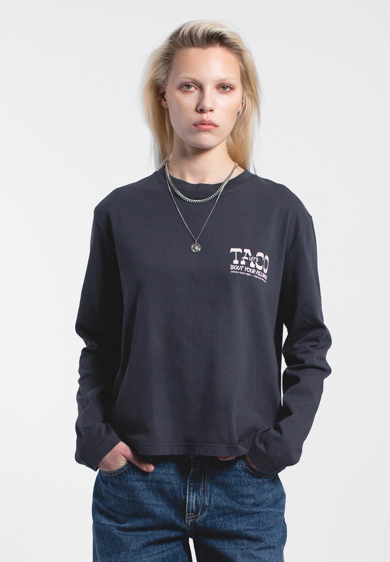 T-shirt a maniche lunghe color navy in cotone, con una grafica frontale e scritte rosa. Vestibilità ampia con scollo rotondo e dettagli sottili sull'orlo.