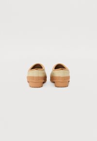 Barna és krém slip-on cipők gumitalppal, texturált díszítéssel és kerek formával, foltmentes dizájnnal.