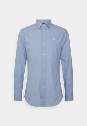 Jasnoniebieska, męska koszula wizytowa z długim rękawem, zapięciem na guziki, ostrym kołnierzem oraz małym białym logo na lewej piersi.