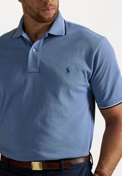 Ανοιχτό μπλε polo με υφή, που διαθέτει τριών κουμπιών και γιακά με ναυτικές ρίγες. Κεντημένο λογότυπο στο στήθος.