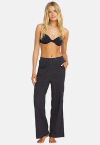 Pantalones negros, ligeros y fluidos con una tela texturizada y una cinturilla elástica, que presentan dos bolsillos laterales y un corte relajado.
