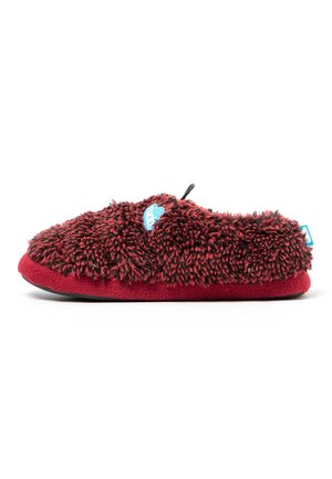 Una única zapatilla peluda roja y negra con suela blanda, un parche azul del logo en la parte superior y una lengüeta en el talón, mostrada de lado.