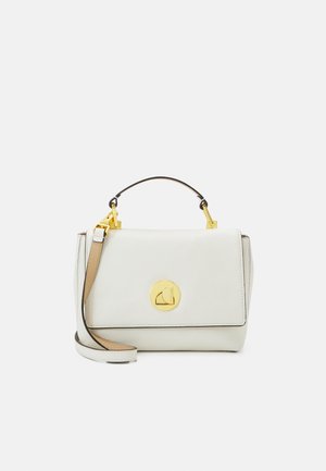 Sac à main en cuir blanc avec fermoir circulaire doré, poignée courte sur le dessus et bandoulière réglable sur fond uni.