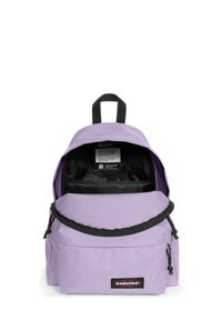 Mochila lila con parte superior redondeada, bolsillo frontal con cremallera y acentos negros. El interior incluye una etiqueta con instrucciones de cuidado. Tejido duradero.