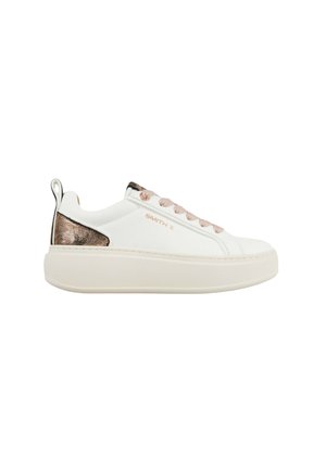 Hvid lavtop sneaker med tyk sål, bronze metalhælaccent, pink snørebånd og "SMITH X" mærkning på siden.