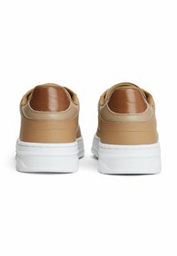 Brune lædersneakers med hvide såler, der har et textured brunt hæl-akcent. Glat materiale og rund form med polstret krave.