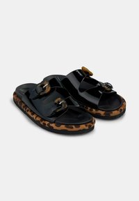 Infradito nere con cinturini lucidi e due fibbie oversize. La suola a motivo leopardato aggiunge contrasto e texture. Materiale in gomma resistente.