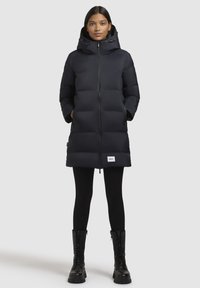 Černá péřová bunda se zipem, kapucí a bočními kapsami. Disponuje prošívaným designem a pátem s logem blízko spodního okraje.