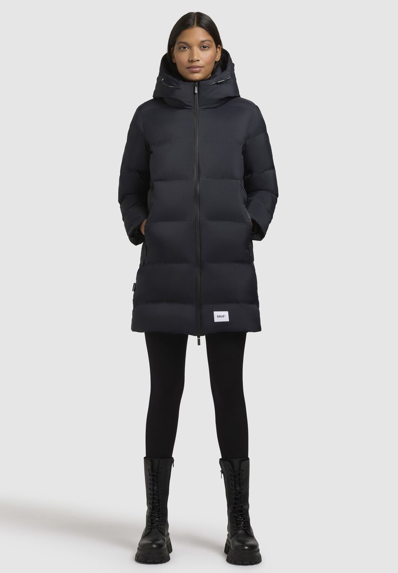 Černá péřová bunda se zipem, kapucí a bočními kapsami. Disponuje prošívaným designem a pátem s logem blízko spodního okraje.