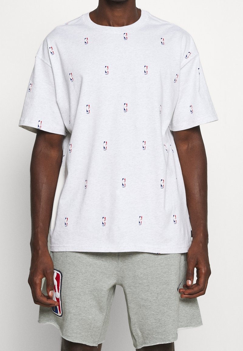Szary bawełniany t-shirt z wzorem logo NBA na całej powierzchni, w małych, kolorowych nadrukach. Posiada okrągły dekolt i luźny krój.
