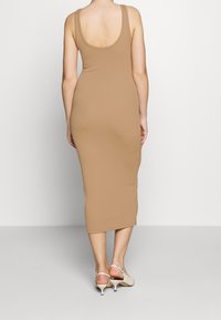 Figurbetontes, ärmelloses Midikleid in Braun, aus glattem Stoff, mit rundem Rückenausschnitt und geradem Schnitt, endet am unteren Wadenbereich.