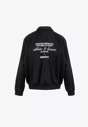 Zwarte sweatshirt met een ontspannen pasvorm, ribgebreide manchetten en zoom, en witte geborduurde tekst op de achterkant met de tekst "sportieve & ontspanningsactiviteiten."