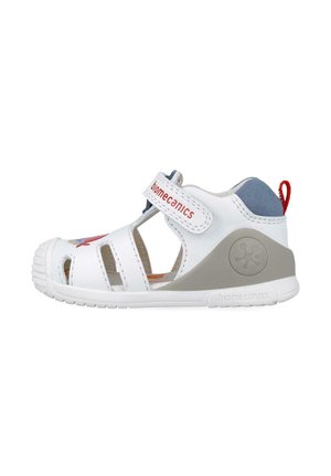 Sandalia blanca con recortes, puntera reforzada, acentos grises, correa de Velcro y logo de marca rojo. Diseño compacto adecuado para uso activo.