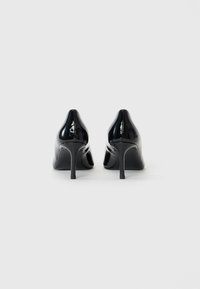 Sorte lakkere høyhælte sko med spiss tå og tynn stiletthæl. Glatt, blank overflate med et elegant design.