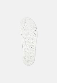 Sole in gomma bianca con motivi circolari di presa e accenti scuri, caratterizzata da dettagli di battistrada prominenti per una maggiore aderenza.