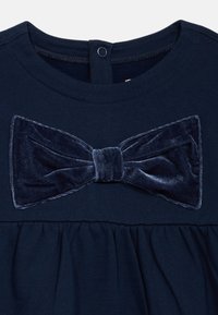 Abito blu navy con un fiocco in velluto testurizzato sul petto e tessuto arricciato in vita, con scollatura tonda e chiusura a bottoni.
