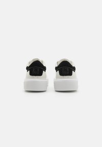 Białe sneakersy z górą ze skóry gładkiej, czarną zamszową zakładką na pięcie oraz białą, teksturowaną gumową podeszwą. Znakowanie "MOP" na pięcie.