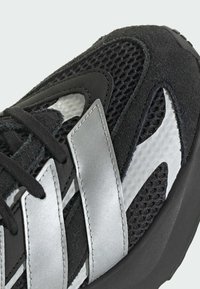 Czarne buty sportowe z siateczki i zamszu, z srebrnymi akcentami, teksturowaną powierzchnią oraz amortyzowaną podeszwą.