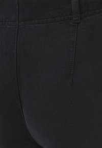 Denim negro con una textura suave, que presenta una silueta ajustada, detalles de costura sutiles y una cintura estándar.