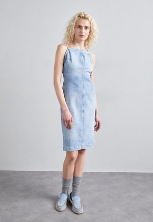 Light blue denim dress with thin straps, fitted design, and visible stitching. Paired with gray socks and blue patterned shoes.