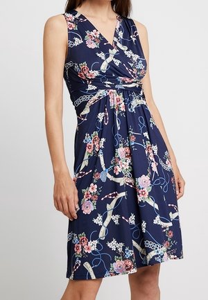 Robe portefeuille bleu marine avec des motifs floraux et de rubans, présentant un décolleté en V, un design sans manches et une taille froncée pour une silhouette fluide.