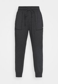 Tummanharmaat jogger-housut, joissa on joustava vyötärö, naru, suuret etutaskut ja käännetyt nilkat, esillä valkoisella taustalla.