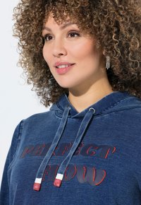 Felpa in denim blu con cappuccio e coulisse, caratterizzata da testo ricamato rosso "PERFECT FLOW" e dettagli testurizzati sul cappuccio.