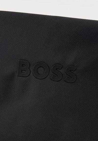 Tissu noir texturé avec lettrage en relief "BOSS" embossé en noir assorti, centré sur le matériau.