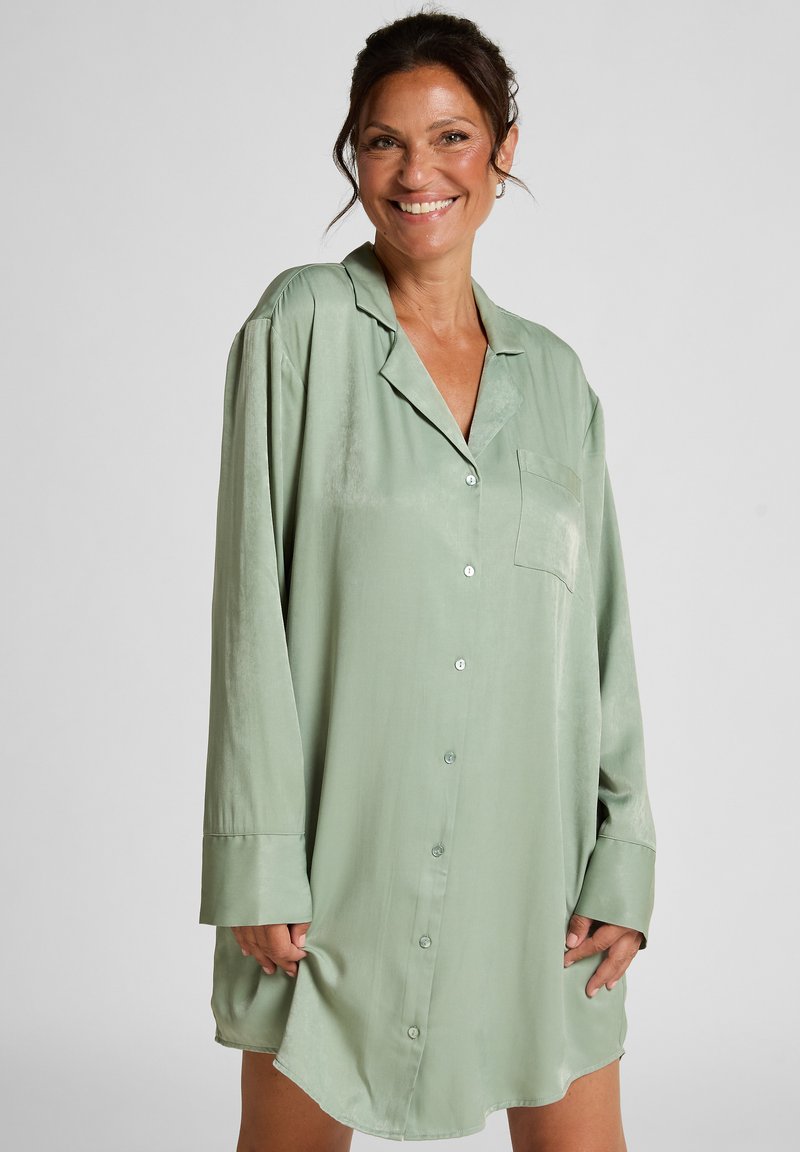 Robe chemise satinée vert clair, à boutons, avec manches longues, une poche poitrine et ourlet arrondi. Texture lisse, coupe décontractée.