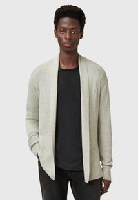 Cardigan a coste grigio chiaro con design aperto, maniche lunghe e vestibilità rilassata. Abbinato a una maglietta nera sotto.