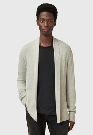 Cardigan a coste grigio chiaro con design aperto, maniche lunghe e vestibilità rilassata. Abbinato a una maglietta nera sotto.
