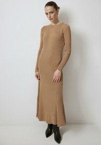 Pikk, sobiv ribikleit heledas pruunis, millel on pikad varrukad, ümar kaelus ja külgjagatud. Kombineeritud mustade terava ninaga saapadega.