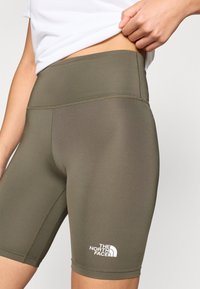 Ελαστικά ποδηλατικά σορτς σε ελιά πράσινο με ψηλή μέση, που διαθέτουν λευκό λογότυπο στην κάτω αριστερή πλευρά. Λείο, εφαρμοστό ύφασμα.