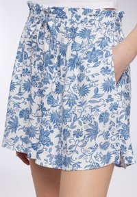 Gonna in tessuto leggero con un motivo floreale blu su sfondo bianco; presenta una vita elasticizzata e tasche laterali.