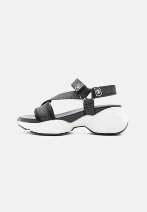 Black and white sporty sandal with thick cushioned sole, adjustable ankle and toe straps, and branded buckle closures.