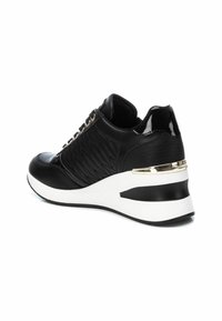 Zapatilla negra con textura acolchada, acentos brillantes, cordones en la parte delantera y una suela wedge blanca con una franja negra y dorada.