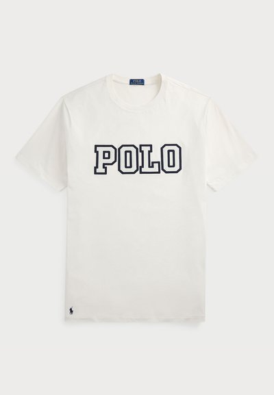 Bílý bavlněný tričko s krátkými rukávy, na přední straně s nápisem "POLO" v námořnické modři a s malým námořnickým logem v dolním levém rohu.