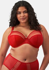 Conjunto de lencería roja que incluye un sujetador con malla semitransparente, bordes en forma de ola y detalles decorativos. La tela es suave y cuenta con aros de soporte.