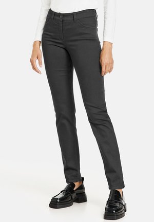 Slim-fit black trousers made of cotton-blend fabric, featuring a five-pocket design and visible stitching details. Worn with glossy black shoes.