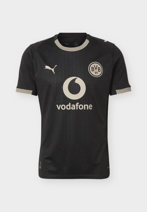 Maillot de football noir du Borussia Dortmund avec logo Puma beige, écusson BVB 09, sponsor Vodafone, et col et poignets de manches à rayures beiges.