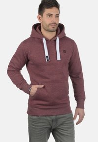 Maronfarvet hoodie med en frontlomme, hvide snore og et logo på brystet. Fremstillet af blødt materiale, har den et klassisk fit og design.