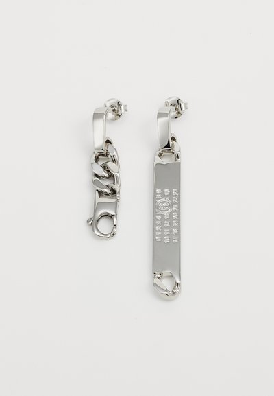 Sølvfargede metalløreringer har en kjedekompisdesign på den ene siden og et flatt rektangulært stykke med pregete merker på den andre siden.