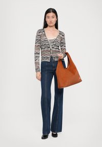 Cardigan a righe in vari colori, abbottonato, abbinato a jeans svasati scuri e una borsa a tracolla in suede marrone. Materiale morbido e design aderente.