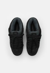 Sorte sneakers med struktureret stof og glatte overflader. Har snørebåndsdesign, polstret tunge og logo på siden. Grå inderside.