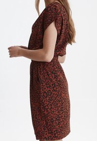 Kortärmad klänning i rostfärgad med svart leopardmönster, med avslappnad passform, elastisk midja och mjuk textile. 