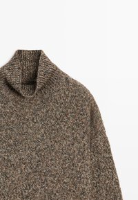 Hnědý pletený svetr s vysokým stojáčkem, s texturovaným vícetonovým vzorem. Textura vypadá měkce a útulně, navržena pro zahřátí.