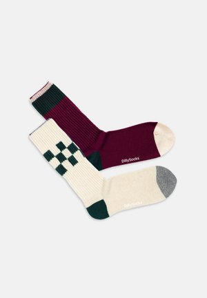 Twee paar sokken: de ene kastanjebruin met ribbelstructuur, de andere roomwit met een groen geruit patroon. Beide hebben contrasterende kleuren voor de tenen.