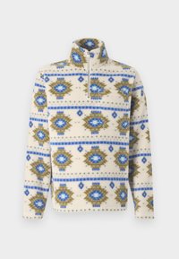 Kerma fleece pullover dengan pola geometris biru dan zaitun, dilengkapi penutup setengah zip di depan, dan kerah tinggi.