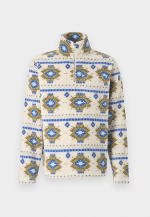 Kreemist fliispullovrist siniste ja oliivroheliste geomeetriliste mustritega, millel on pooltõmblukk ees ja kõrge krae.